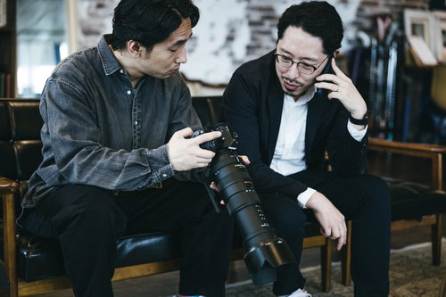 証拠写真を確認しながら依頼人に電話する探偵の二人