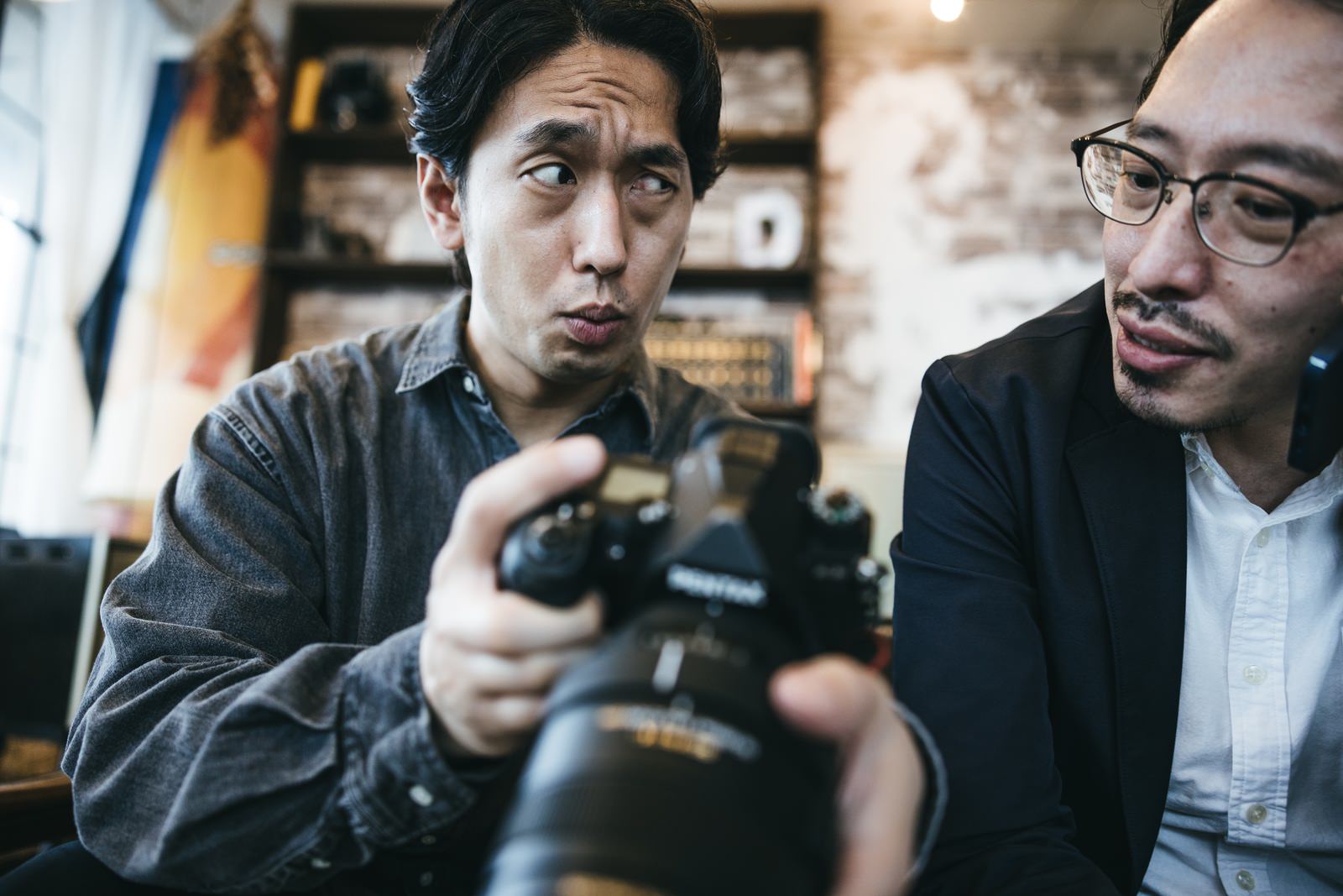 一眼レフを見せる男性カメラマンと相棒［モデル：大川竜弥 ゆうせい］