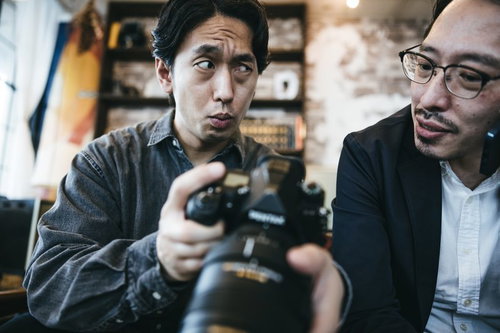 クライアントに写真の出来を確認する男性カメラマン