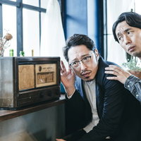 ラジオに耳を傾ける二人組の探偵調査員の張り込み調査の写真