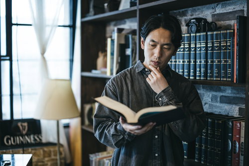 分厚い百科事典を広げて調べる男性の学習風景