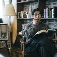 調べ物をしながら虫メガネを右目に当てる男性の写真