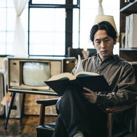 本棚に囲まれた書斎で洋書を調べる男性の集中力の写真