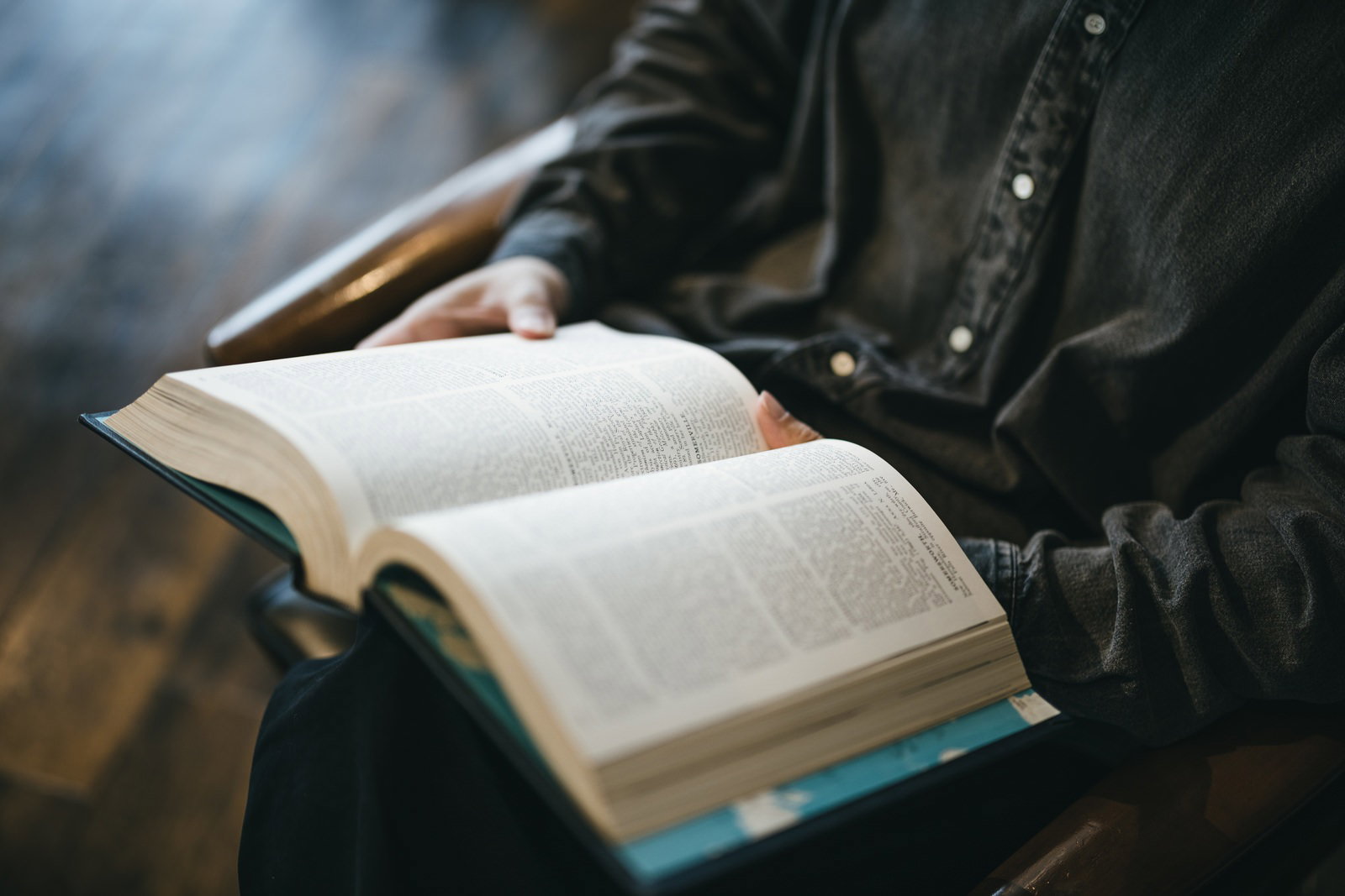 開いた洋書のページに手を添えて読書している様子