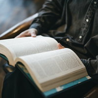 図書館で開いた本のページをめくる手元の読書風景の写真