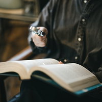 聖書をルーペで調べものをする手元の研究風景の写真