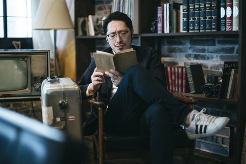 スーツケースと読書を楽しむ男性