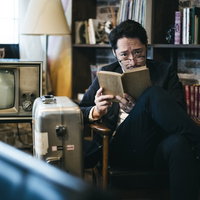 読書している風を装い張り込みする探偵男性の写真