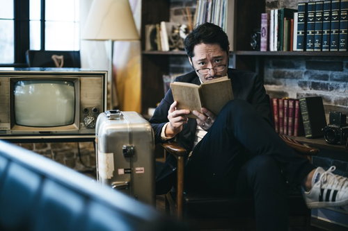 読書している風を装い張り込みする探偵男性