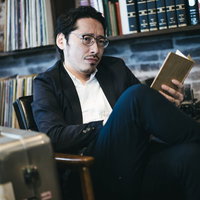 図書館で読書に集中できない眼鏡をかけた黒いスーツの男性の写真