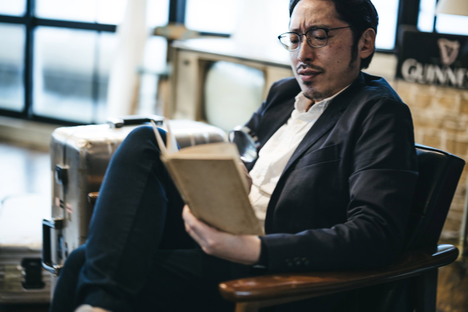 スーツを着た男性が拡大鏡を使って調べものをしている［モデル：ゆうせい］