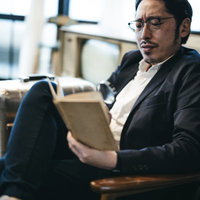 スーツ姿で拡大鏡を覗き込み調べものをする男性の写真