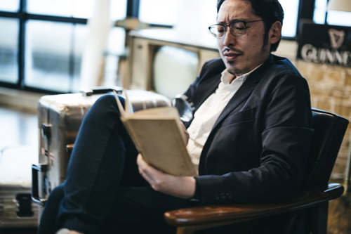 スーツ姿で拡大鏡を覗き込み調べものをする男性