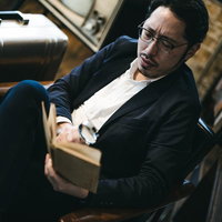 拡大鏡を片手に図書館で本を読む男性の集中した様子の写真