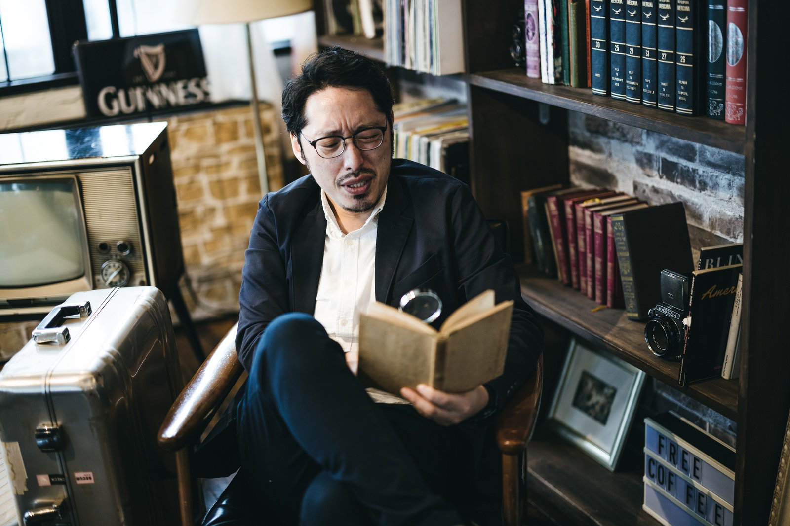 本棚の前で眼鏡をかけて読書に集中する男性［モデル：ゆうせい］