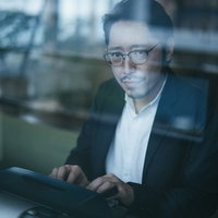 眼鏡をかけながらタイプライターで報告書を作る男性の写真