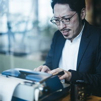 眼鏡をかけてしかめっ面でタイプライターをたたく男性の写真