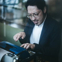 しかめっ面でタイプライターのキーを操作する男性の手元の写真