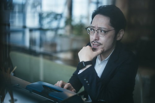 タイプライターの前で考え込む探偵男性メガネ