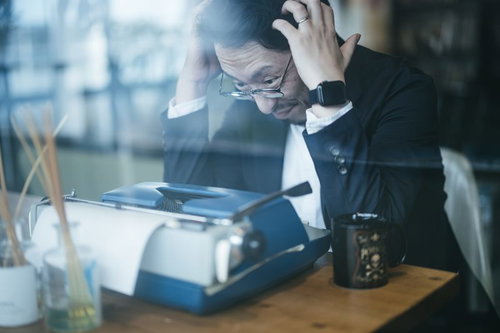 タイプライターの前で頭を抱えて考える男性