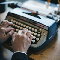 タイプライターを打鍵する指輪をした手元のの写真