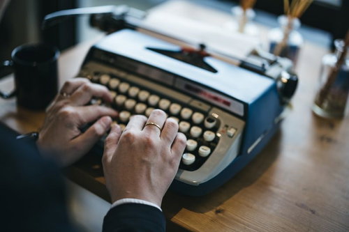 タイプライターを打鍵する指輪をした手元の