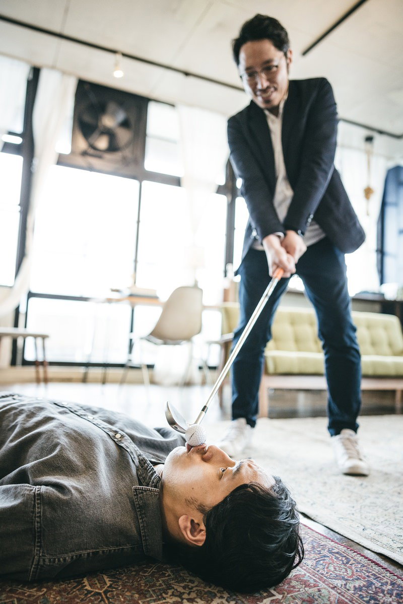 ゴルフクラブのアイアンを持って床に倒れた人物を威嚇するスーツ姿の男性［モデル：ゆうせい 大川竜弥］