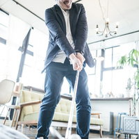 室内でアイアンを構えて脅迫する男性の威嚇的な表情の写真