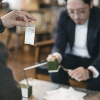 パケに入った白い粉（片栗粉）を相棒に見せる男性の写真