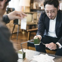 白い粉（片栗粉）をパケに詰める作業をする男性の写真