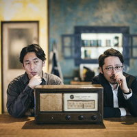 古いラジオを前に落ち込む二人組の探偵の写真