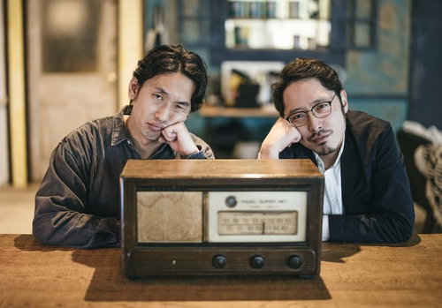 アンティークラジオを挟んで頬杖をつく二人組の探偵