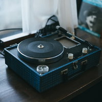 窓辺に置かれた黒いレコードプレーヤーとターンテーブルの写真