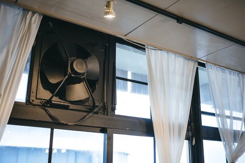 白いカーテンが揺れる窓際の大型換気扇