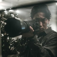 部屋の一室から望遠レンズで激写する男性フォトグラファーの写真