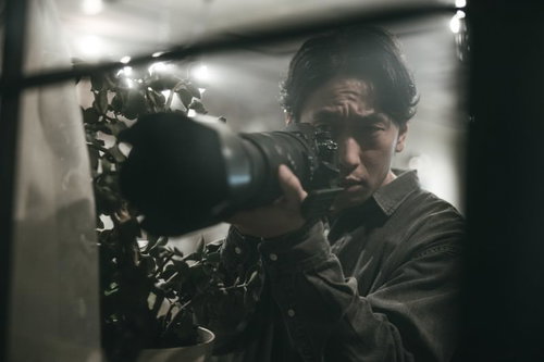 部屋の一室から望遠レンズで激写する男性フォトグラファー