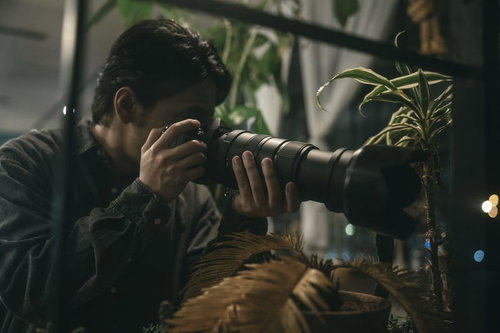 カメラを構える張り込み中の警察官の監視捜査