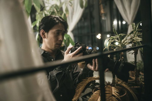 窓辺からカメラで狙うパパラッチ男性の調査