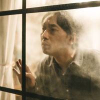 窓ガラス越しにのぞき見する男性の真剣な表情の写真