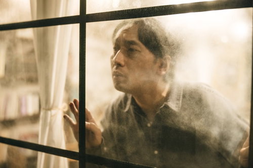 窓ガラス越しにのぞき見する男性の真剣な表情