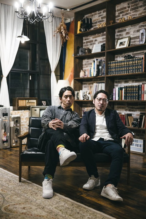 ブリックスタイルの部屋で腰掛けて睨みつける二人組