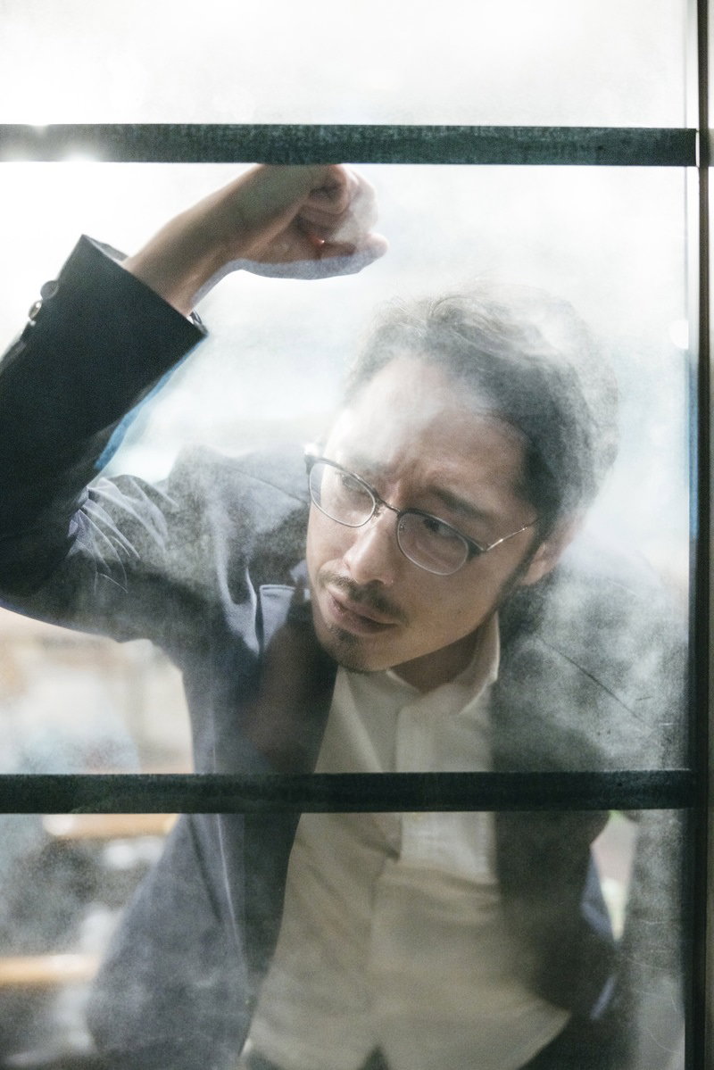 窓をたたいて落胆する眼鏡をかけた男性が下を向いている［モデル：ゆうせい］