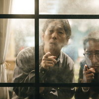 窓辺から張り込み中の二人組の探偵が指を差して作戦を立てるの写真