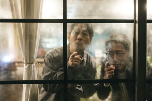 窓越しに対象者を目視する二人の探偵による張り込み調査