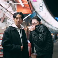 都橋商店街の夜間に立つ探偵姿の男性2人が会話する下町風景の写真