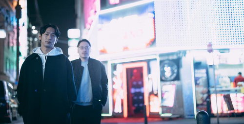 ネオンが輝く繁華街の店先で事情聴取する二人組の男性