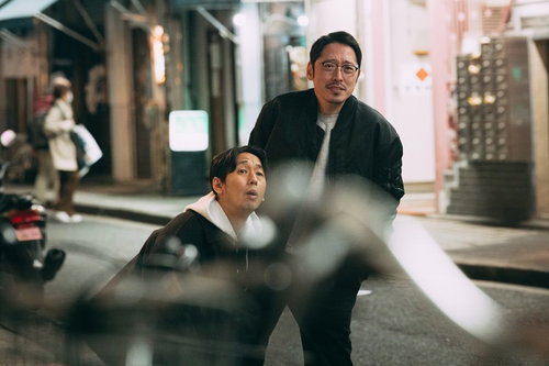 夜の街で調査対象を追跡する探偵ふたりの尾行監視