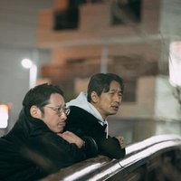 夜間の街で尾行と見張りを語る二人組の探偵の写真