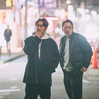 夜の街を徘徊する2人組の男性が立ち話をする深夜の繁華街の写真