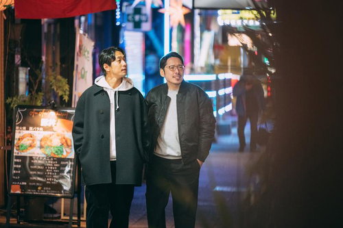 夜の路地で徘徊する2人組の男性、ネオン看板が輝く繁華街